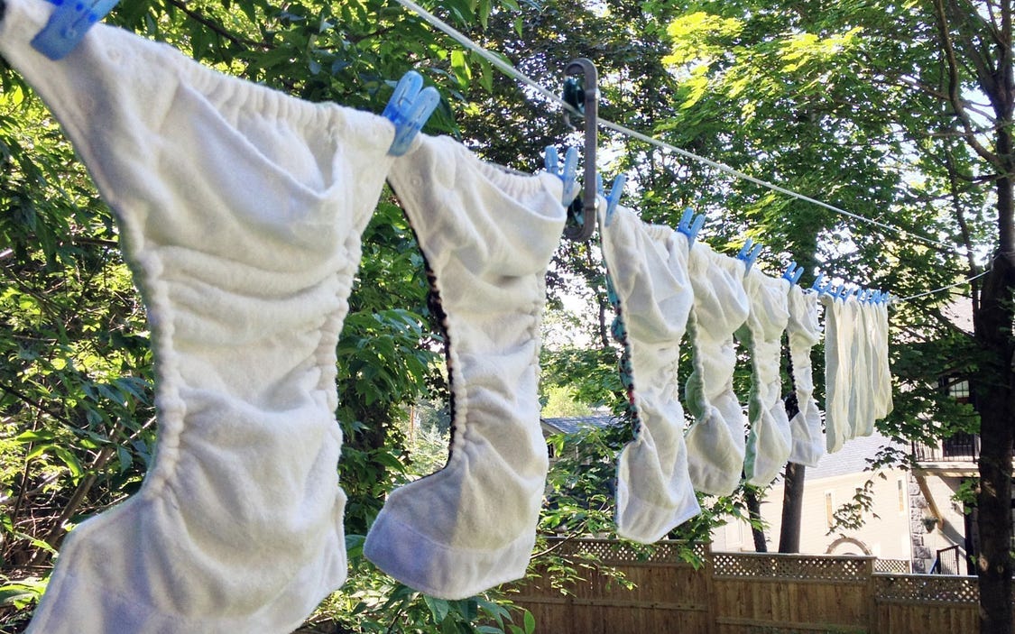 a row of whiite plastic diaper covers hanging on a clothes line