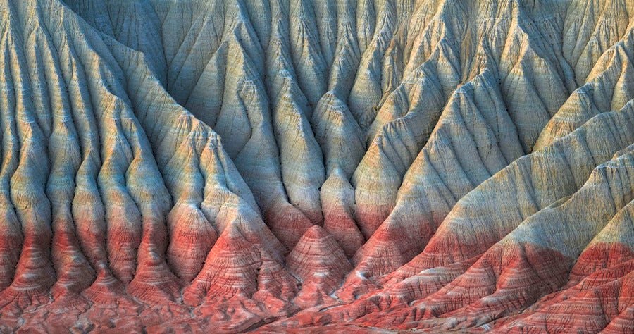 A rugged, highly eroded canyon wall, exposing multiple different-colored layers of stone A rugged, highly eroded canyon wall, exposing multiple different-colored layers of stone