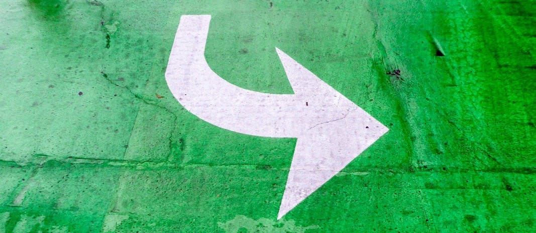 a white arrow painted on a green parking lot