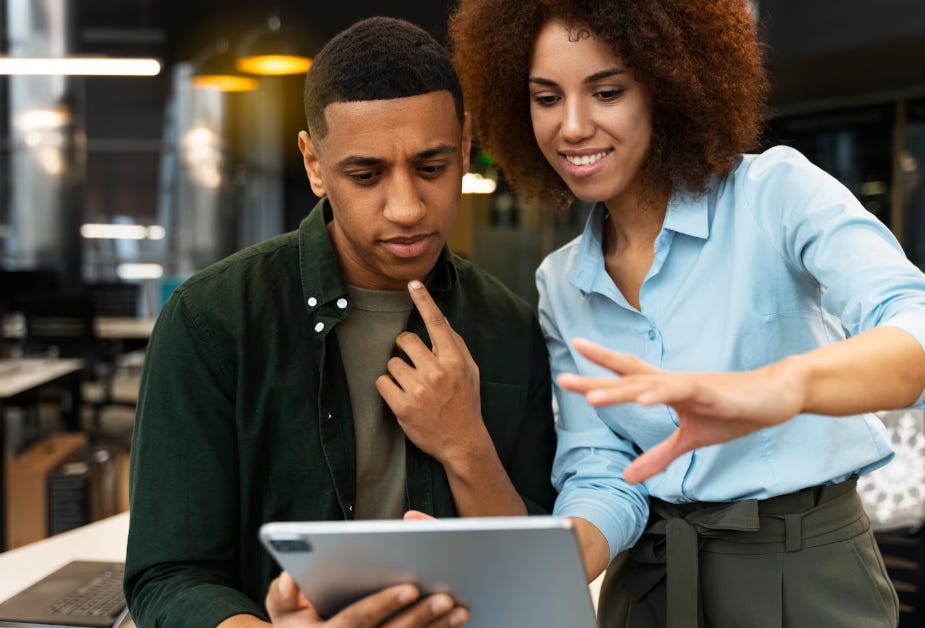 Two black individuals looking at an iPad. Two black individuals looking at an iPad.