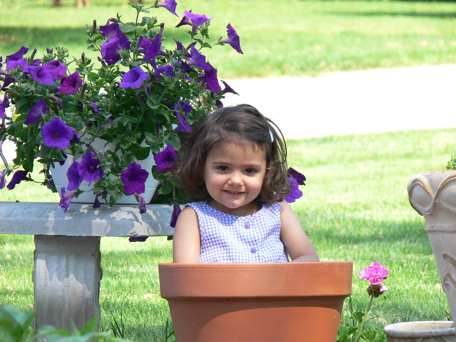 a young girl sitting in a plant pot