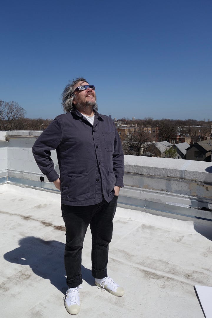 Jeff squints at the solar eclipse while wearing protective glasses; Jeff looks at the camera from a clawfoot bathtub; Jeff smiles with regular- and mini-size copies of the Wilco LP Cousin; Jeff feeds Icelandic horses