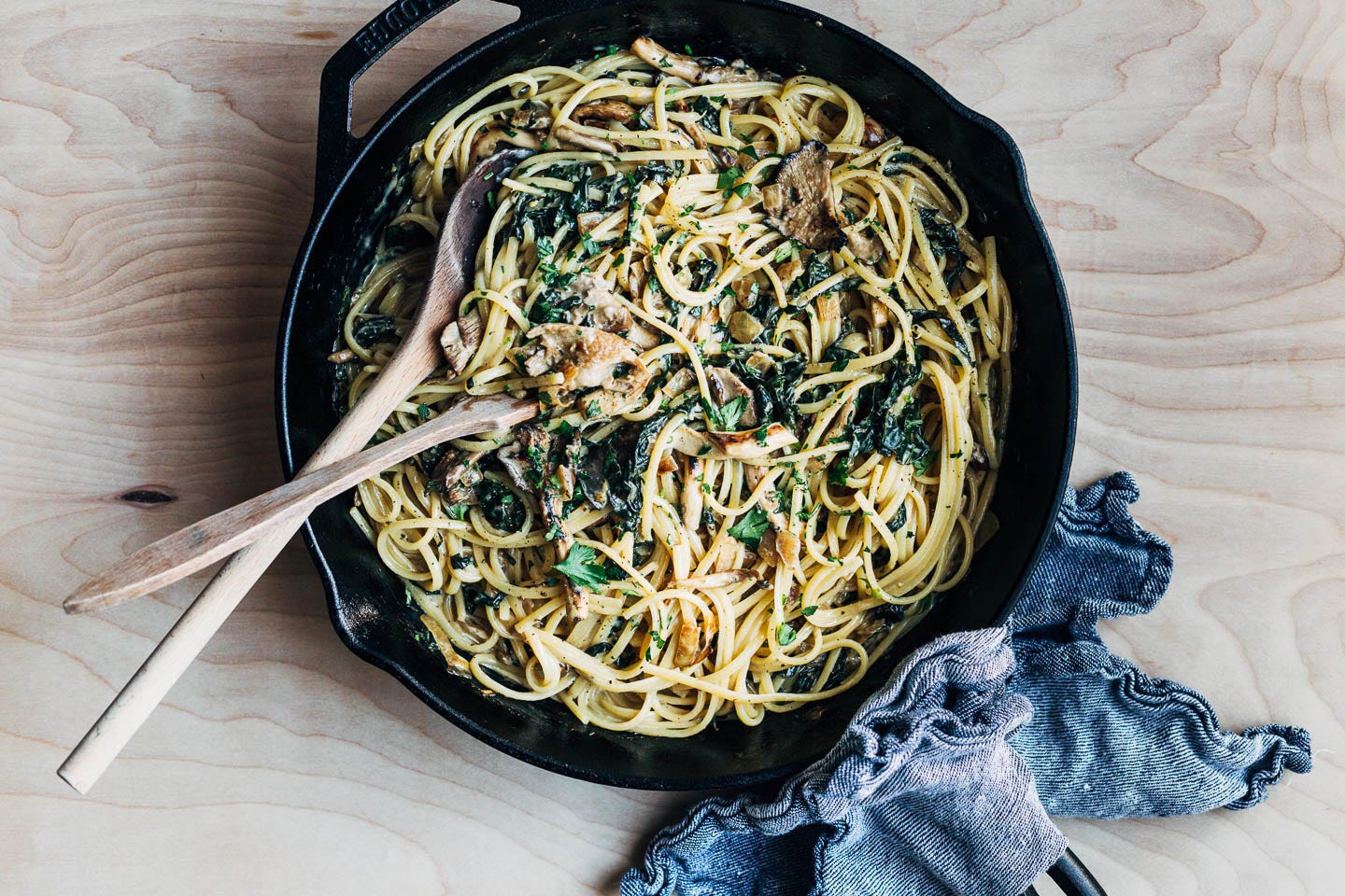 A cast iron skillet full of creamy mushroom and greens pasta. 