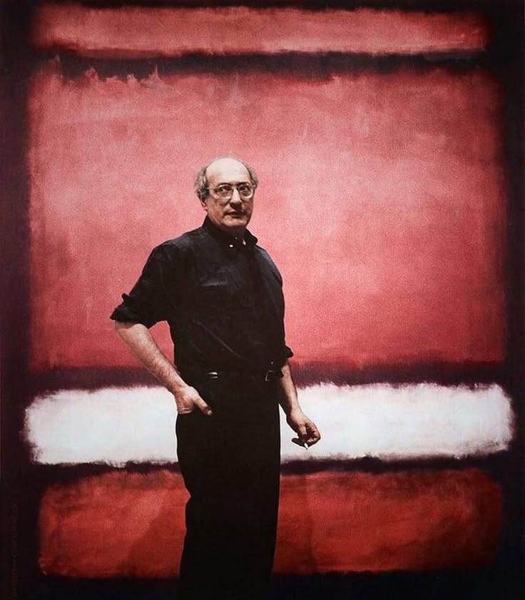This may contain: a man standing in front of a red and white painting with his hands on his hips