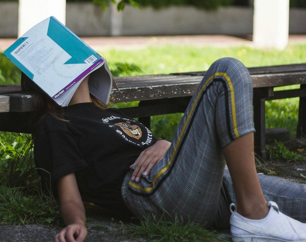 Image of someone lying sleeping with a book covering their eyes Image of someone lying sleeping with a book covering their eyes
