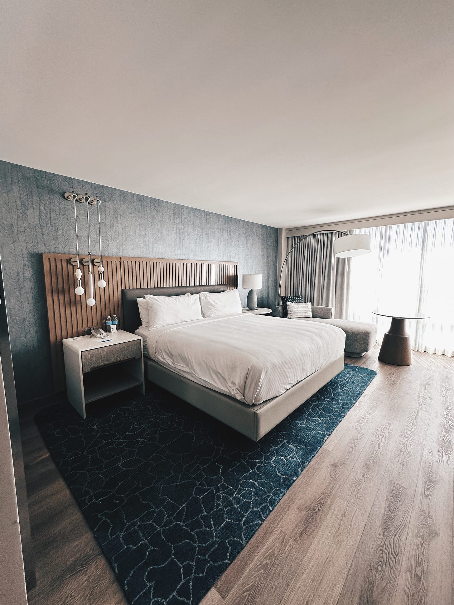 Modern coastal hotel room interior at VEA Newport Beach with navy blue rug and white bedding