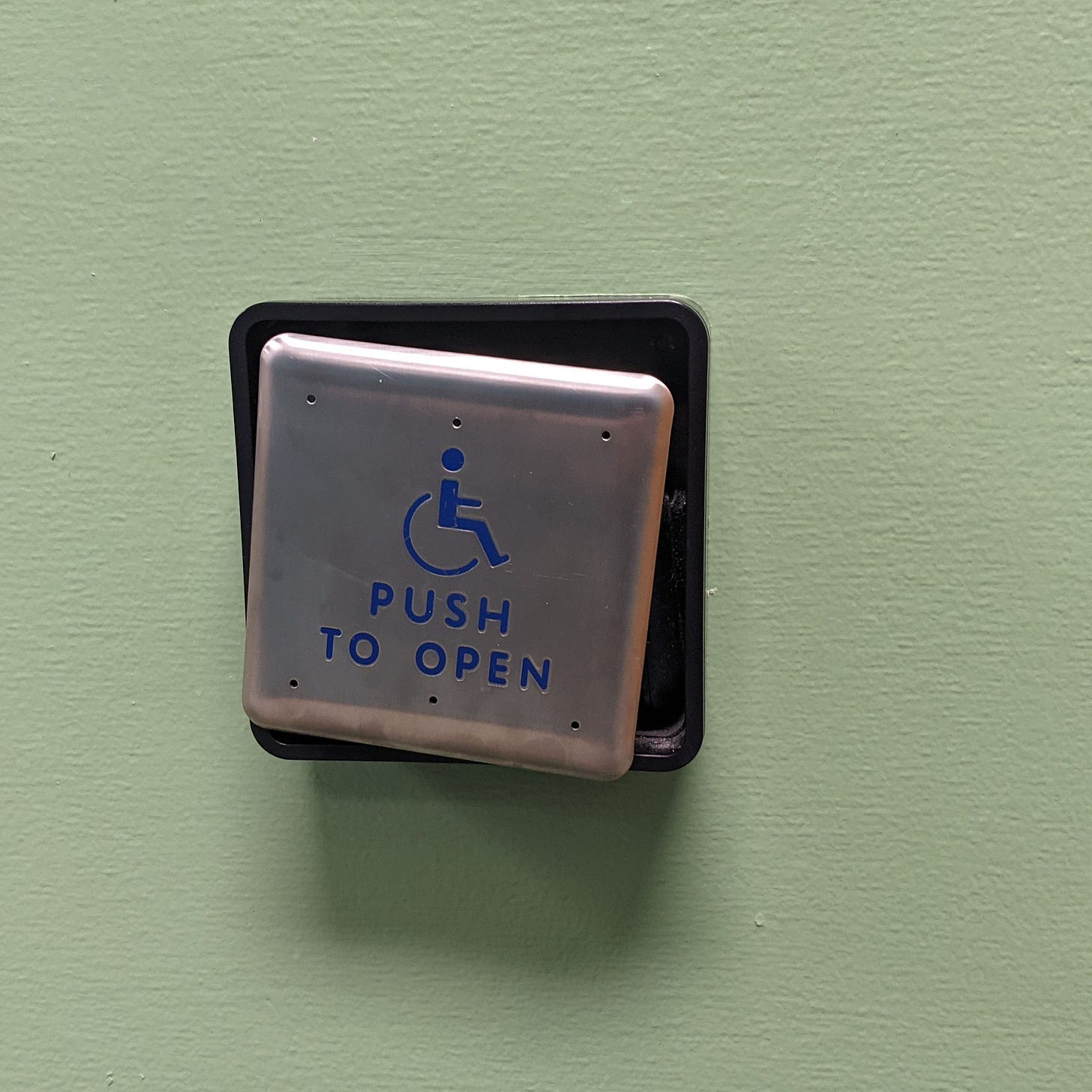 an A D A push button slightly broken, so the exterior of the button is hanging down on one side