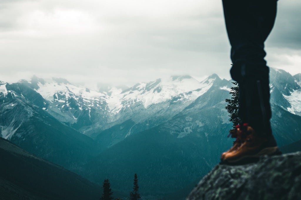 A woman standing on a rock looking at the far mountains