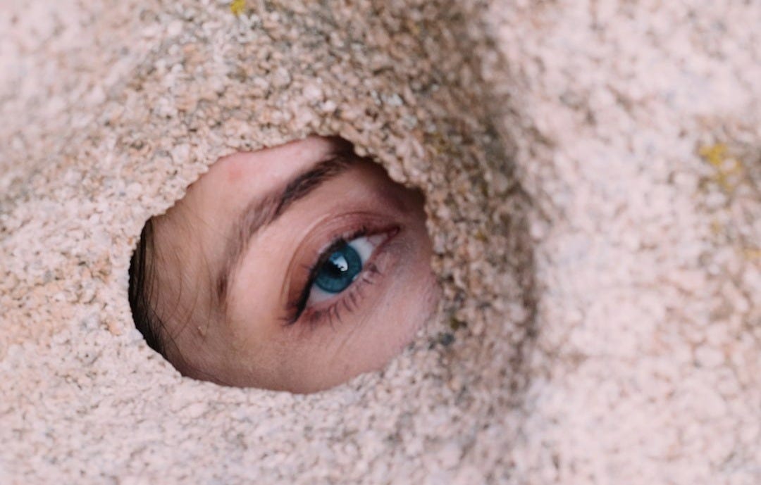 a close up of a person's eye through a hole in the sand
