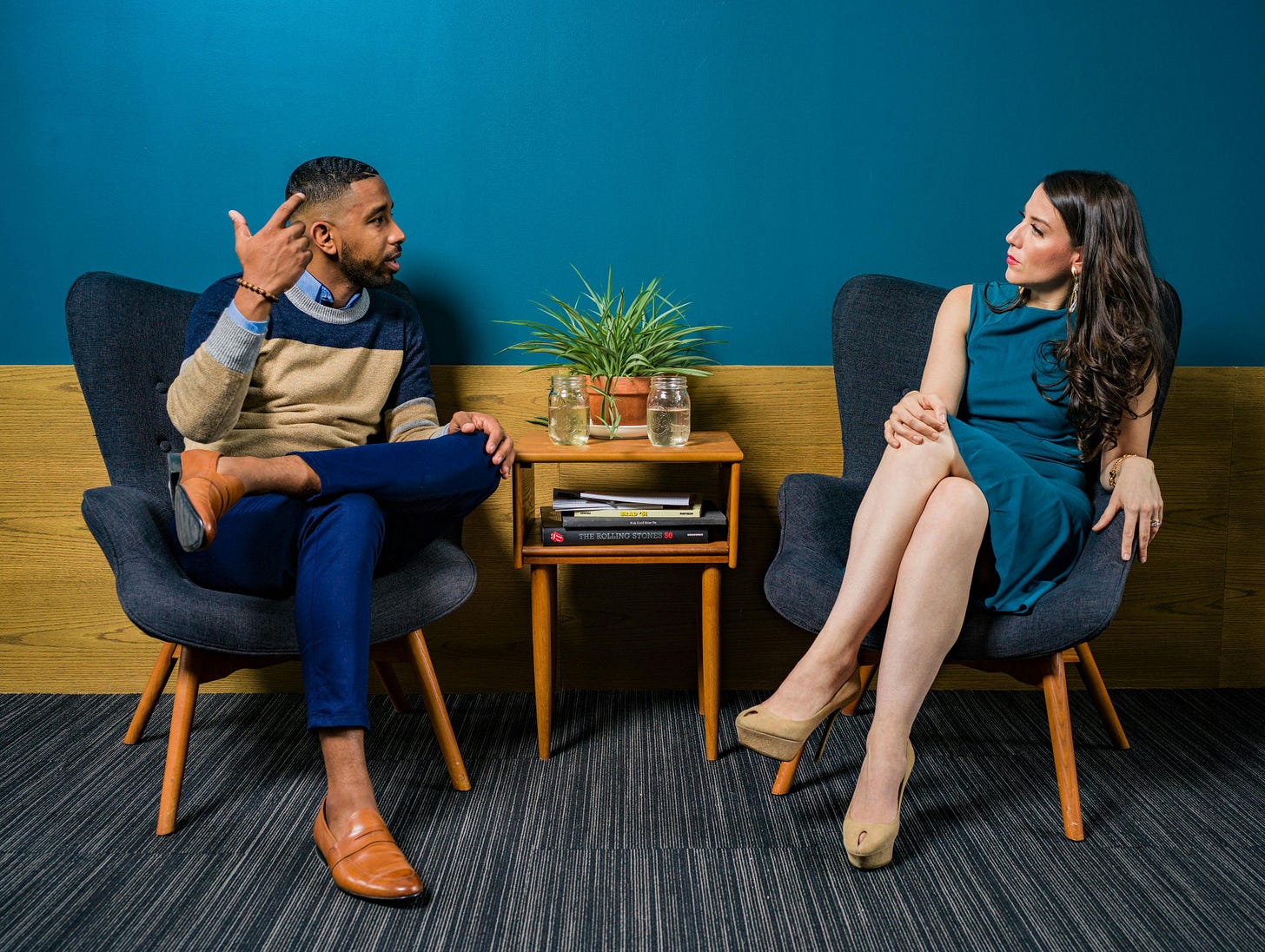 Woman and man sitting in chairs and talking with small table between them