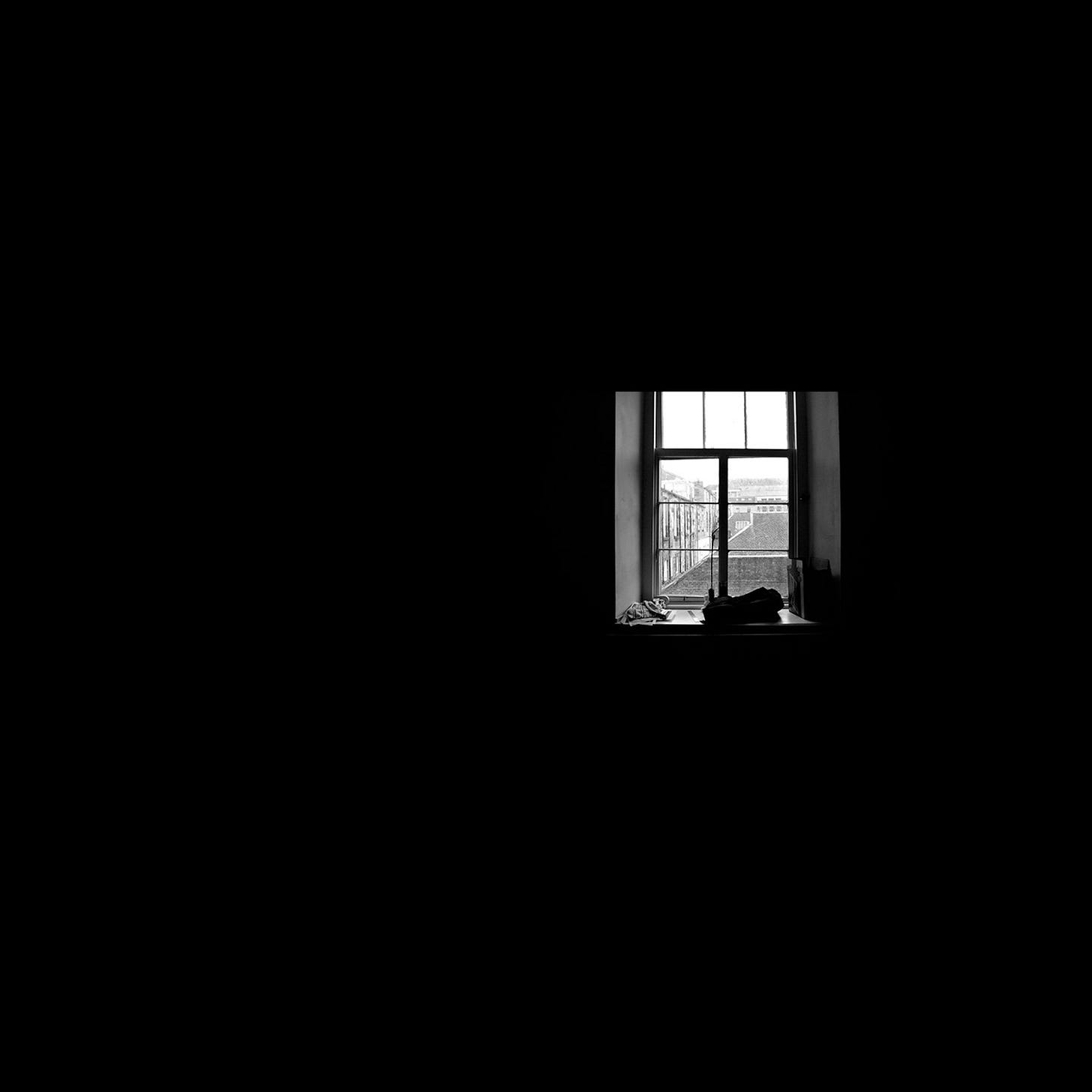 A window in a dark room, looking out on a gray city