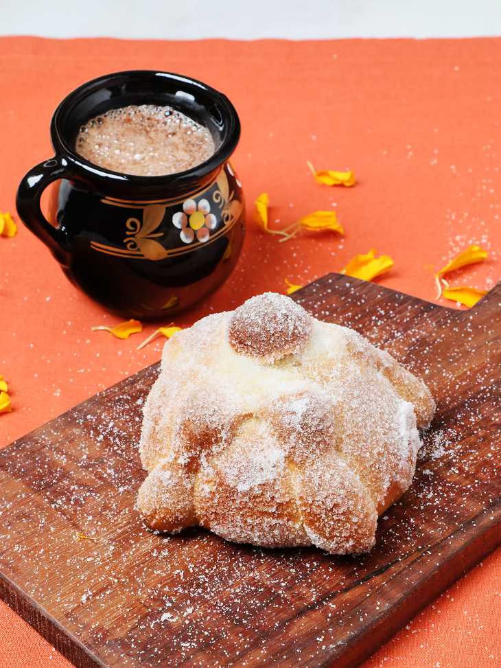 A cup of hot chocolate and a loaf of pan de muerto