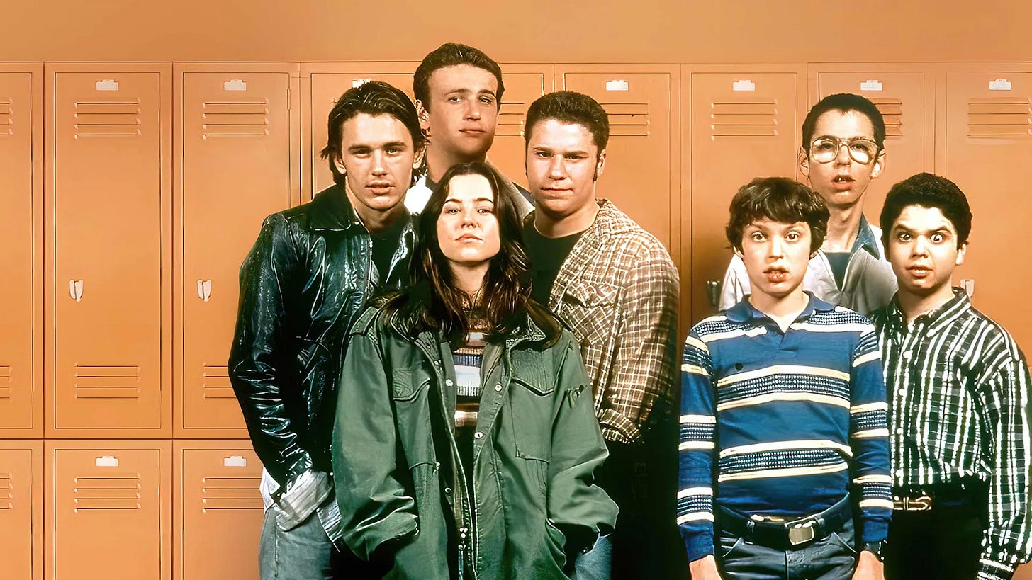 Cast photo from Freaks and Geeks showing seven teenagers standing in front of orange school lockers.