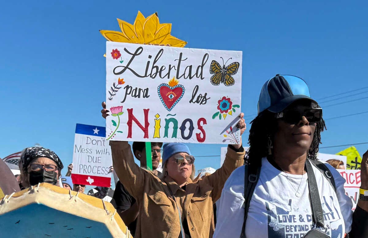 A protester holds a sign calling for freedom for children during a demonstration and vigil outside the South Texas Family Residential Center in Dilley, Texas, on January 28, 2026.