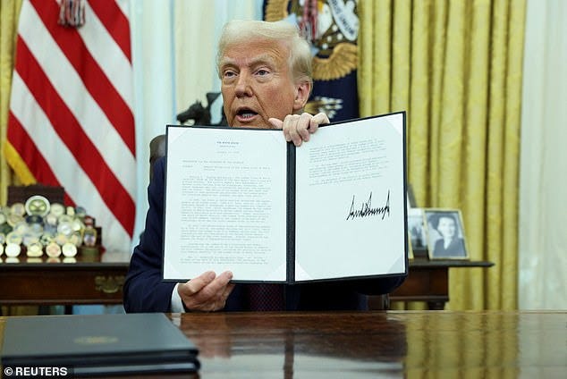 U.S. President Donald Trump holds a signed executive order in the Oval Office of the White House, in Washington, U.S., January 23, 2025.