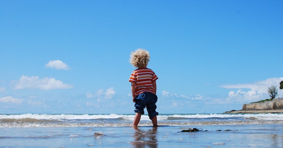 child standing on body of water