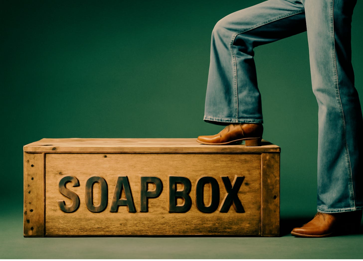 A woman in jeans and cowboy boots stepping onto a wooden soapbox; only her legs are visible.