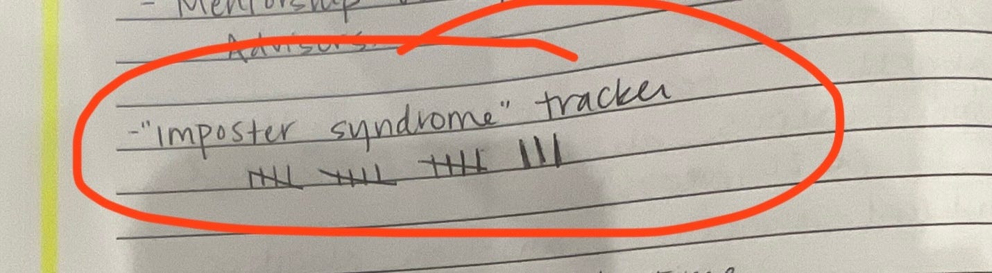 Image of a college-ruled notebook with the words "imposter syndrome tracker" handwritten with 18 hashmarks underneath.