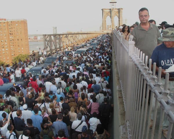Many people crowded around a line of cars on the Brooklyn Bridge. Many people crowded around a line of cars on the Brooklyn Bridge.