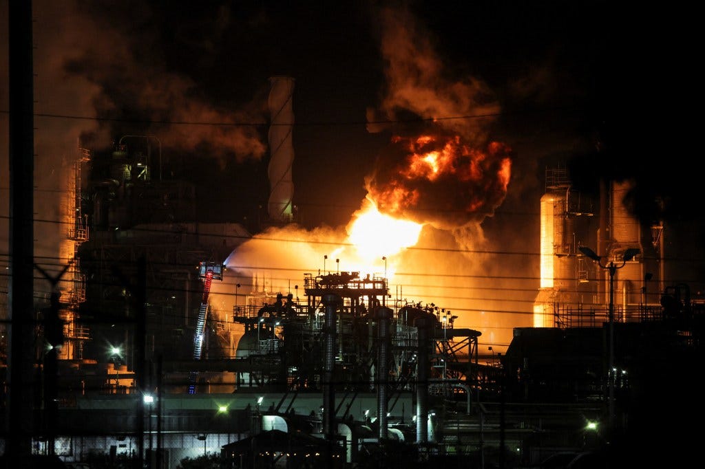 Clouds of smoke and flames illuminate the night sky during a fire at a refinery location.