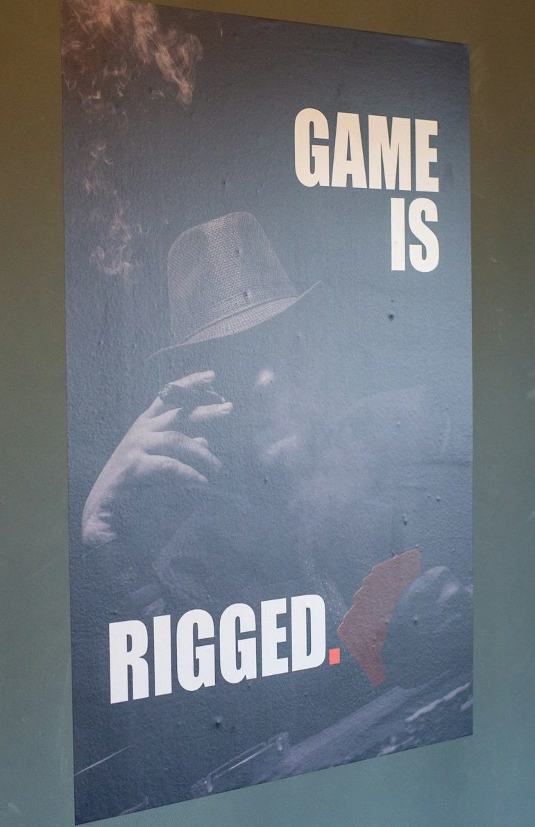 Poster with text 'game is rigged' and man.