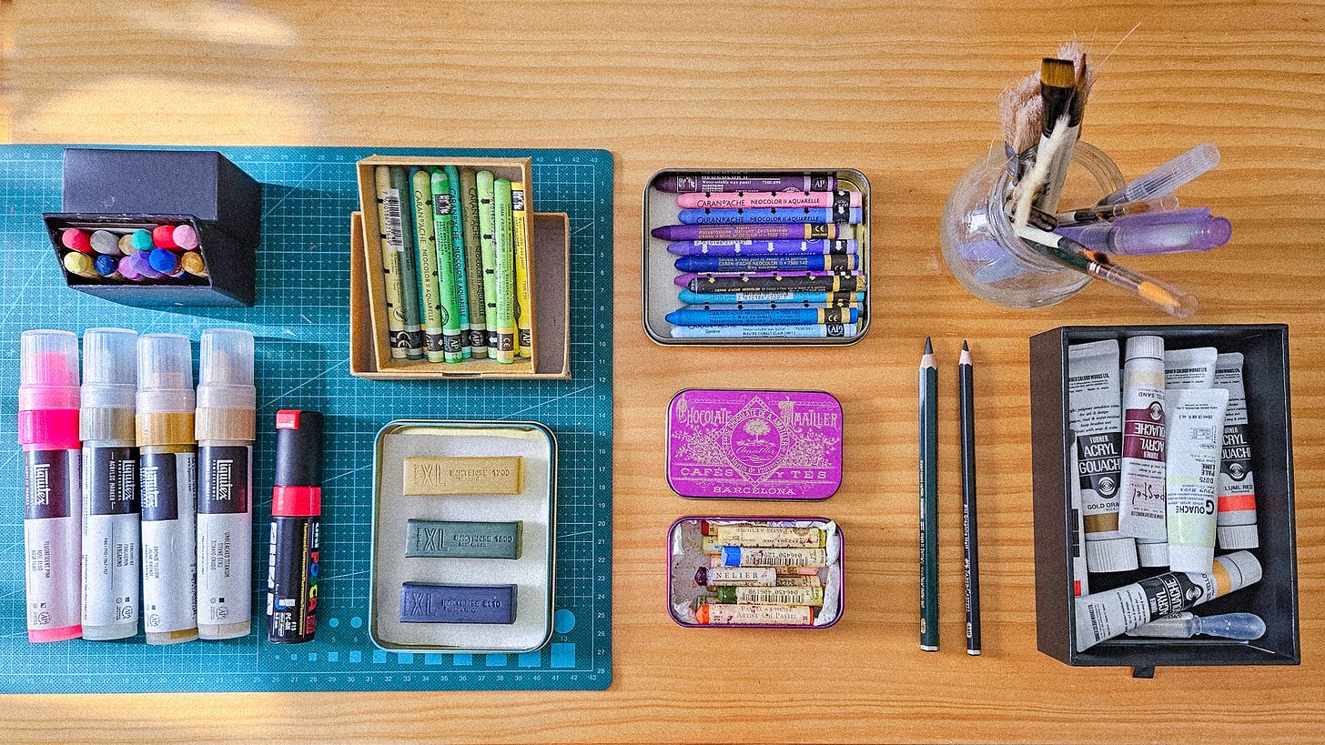 Different art supplies in reused containers like chocolates tins boxes, tech packaging, food jar, etc.