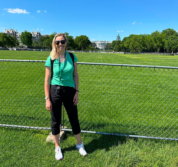 Author standing in the distant front of the White House, and petting a fluffy black dog in her lap.