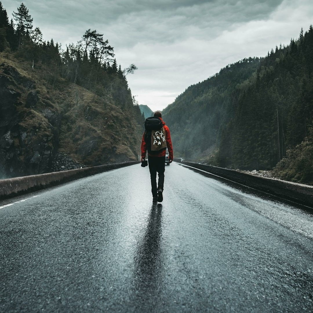person in black jacket and black pants walking on road during daytime