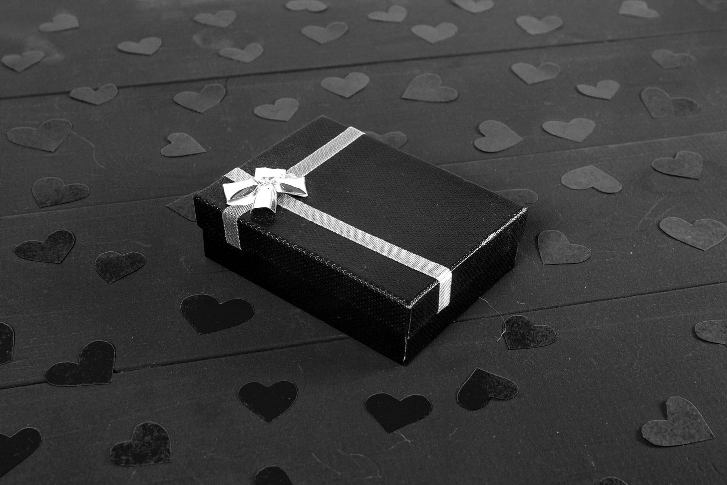 a blue gift box with a bow on a black surface with red hearts a blue gift box with a bow on a black surface with red hearts