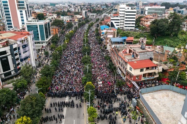 Crowds of people fill both sides of a highway stretching through a city.