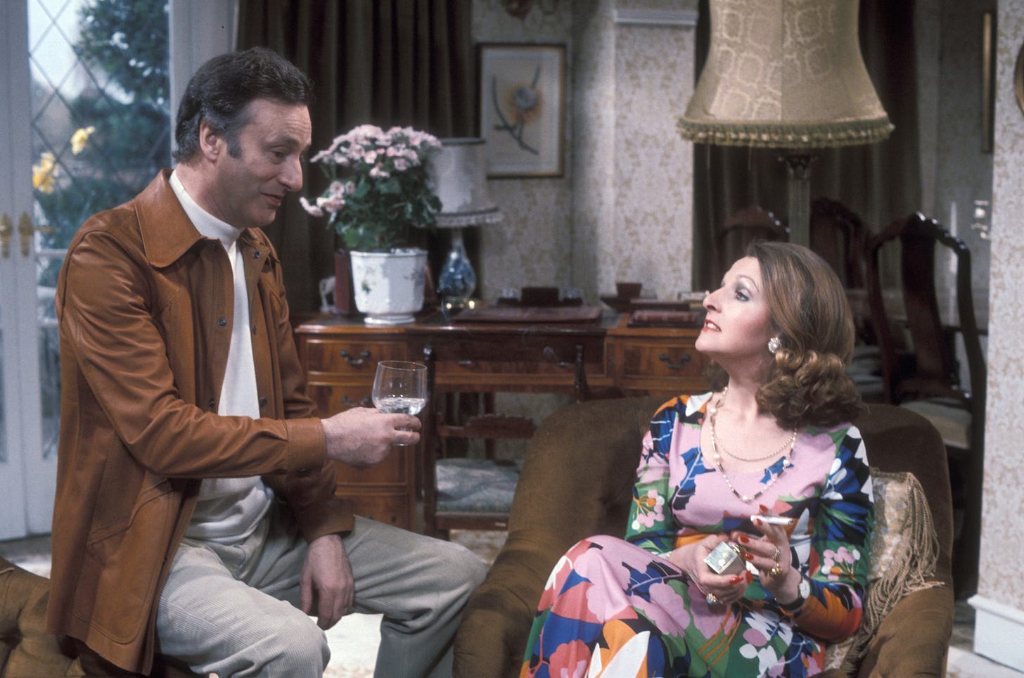 Penelope Keith as Margo and Paul eddington as Jerry during cocktail hour, margo is in a loud dress and is smoking a cigarette Penelope Keith as Margo and Paul eddington as Jerry during cocktail hour, margo is in a loud dress and is smoking a cigarette