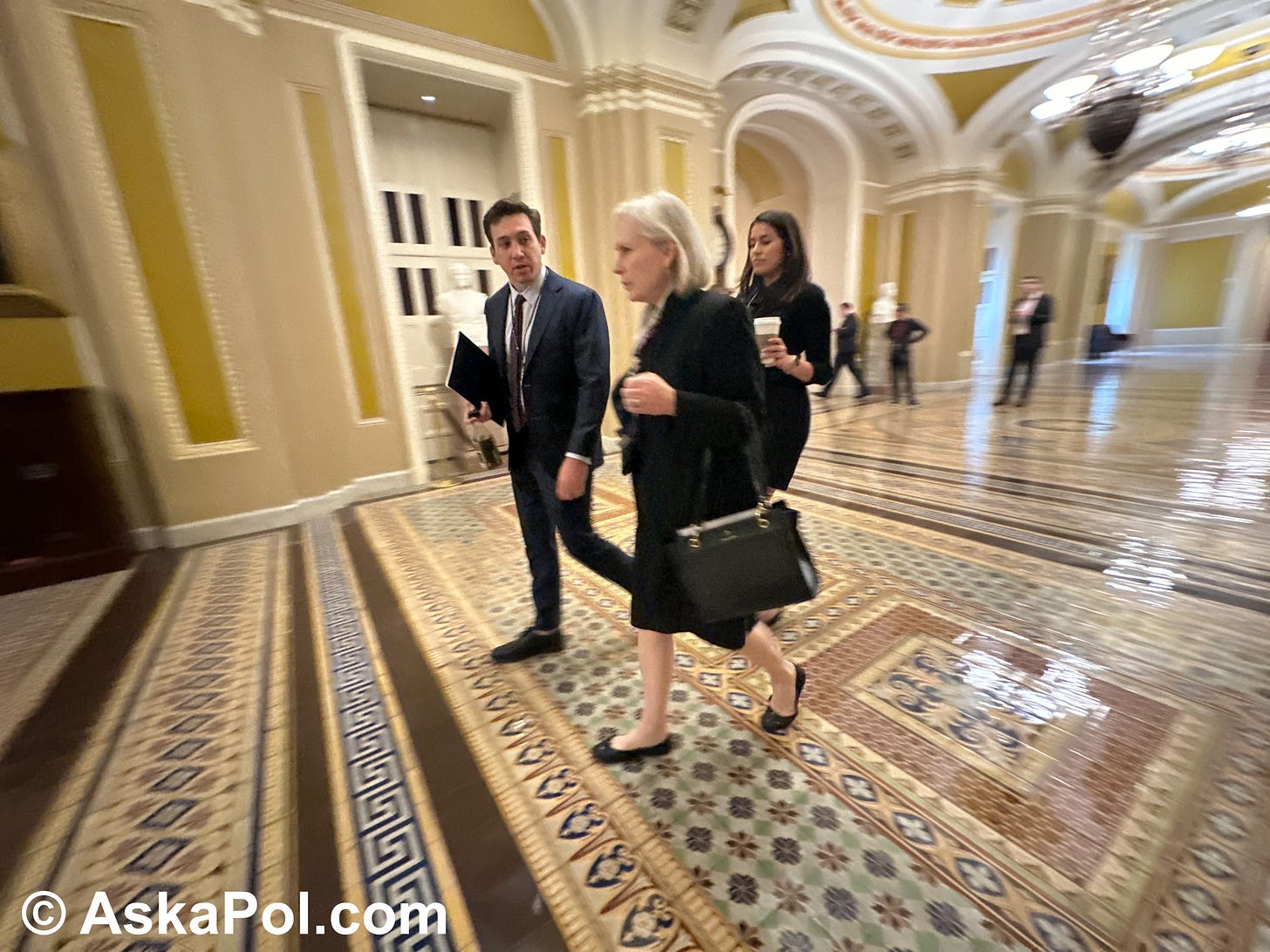 A female Senator and her aides walk quickly through the marble halls of US Capitol Photo © www.askapolcrypto.com