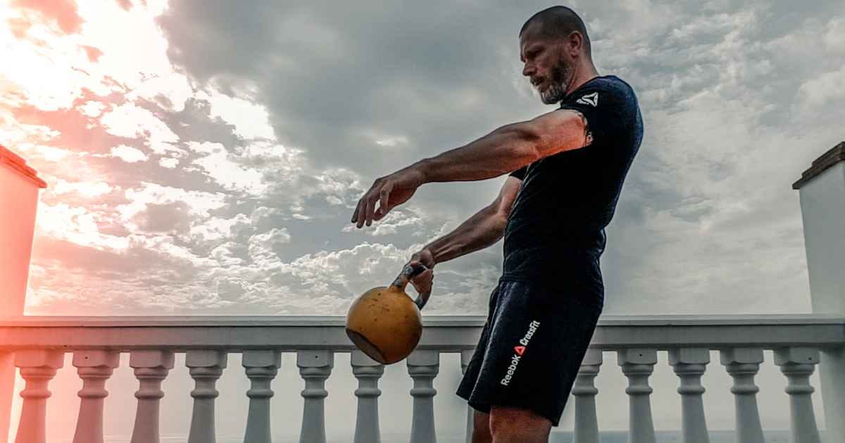man in a black shirt doing a single arm kettlebell swing