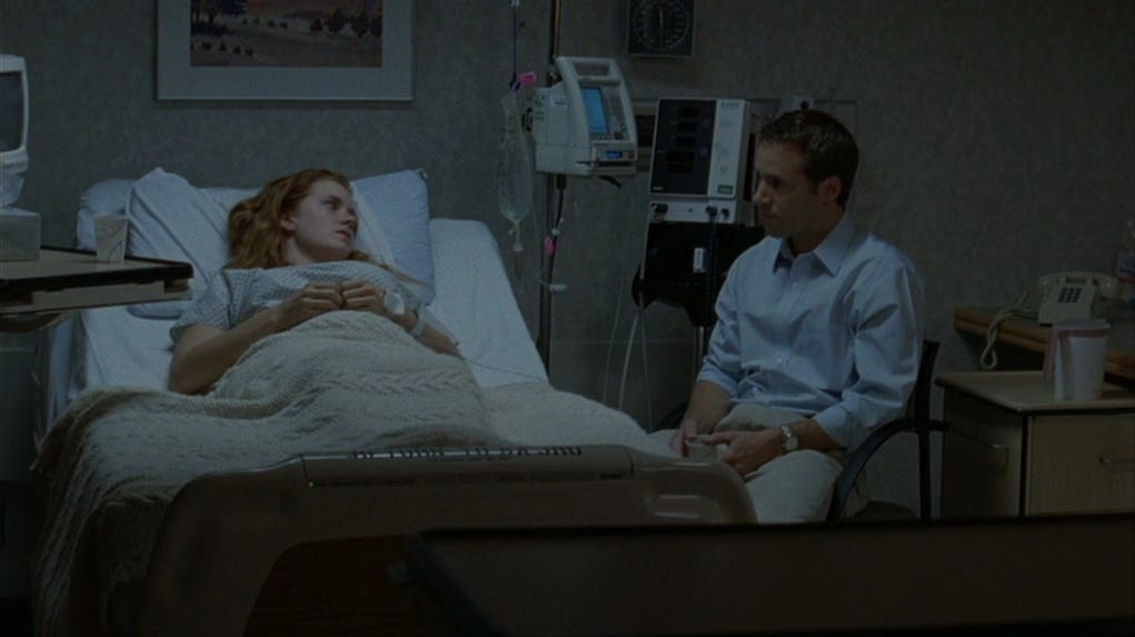 Amy Adams plays Ashley, who lies in a hospital bed following the loss of her child. Her brother-in-law, played by Nivola, sits to her right. 