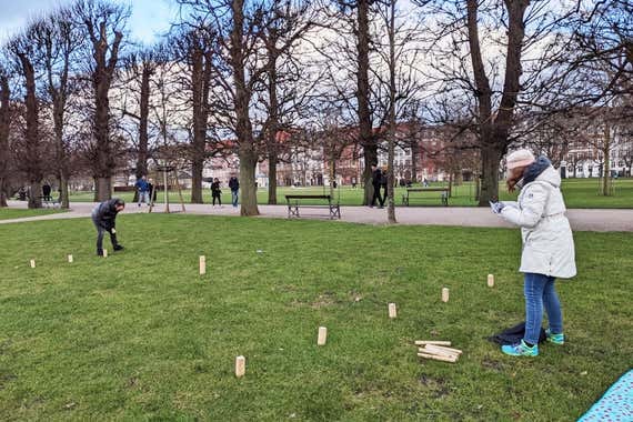 Two people setting up a game of kubb in a park.