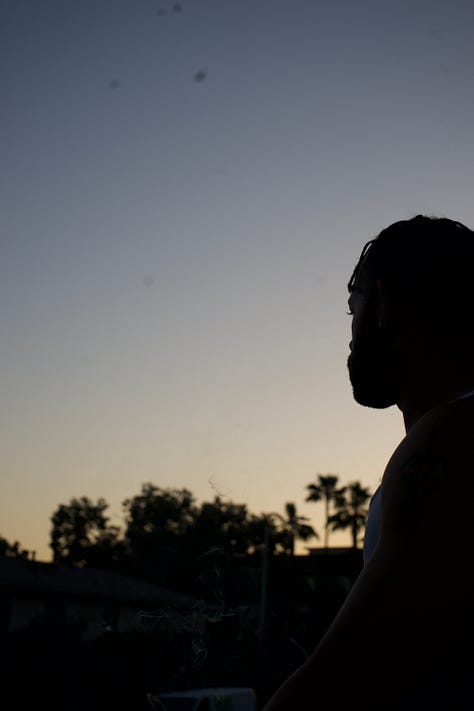 A collection of moody, low-lit photographs including a carefully arranged writing table with tea and ink, stacked journals on rumpled sheets, and a contemplative silhouette at sunset. The images balance structure and softness, suggesting ritual, reflection, and quiet becoming.