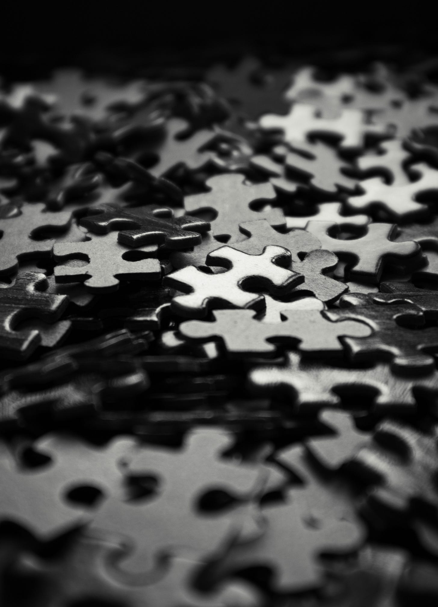 A close-up of scattered black-and-white puzzle pieces, some in focus and others blurred.