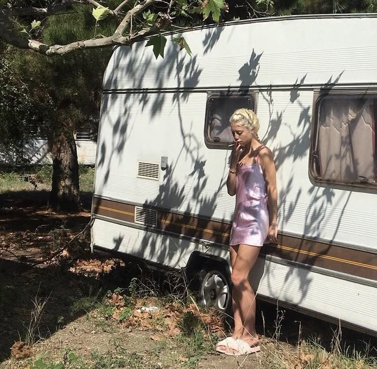 This may contain: a woman standing in front of a trailer talking on a cell phone while wearing pink shorts