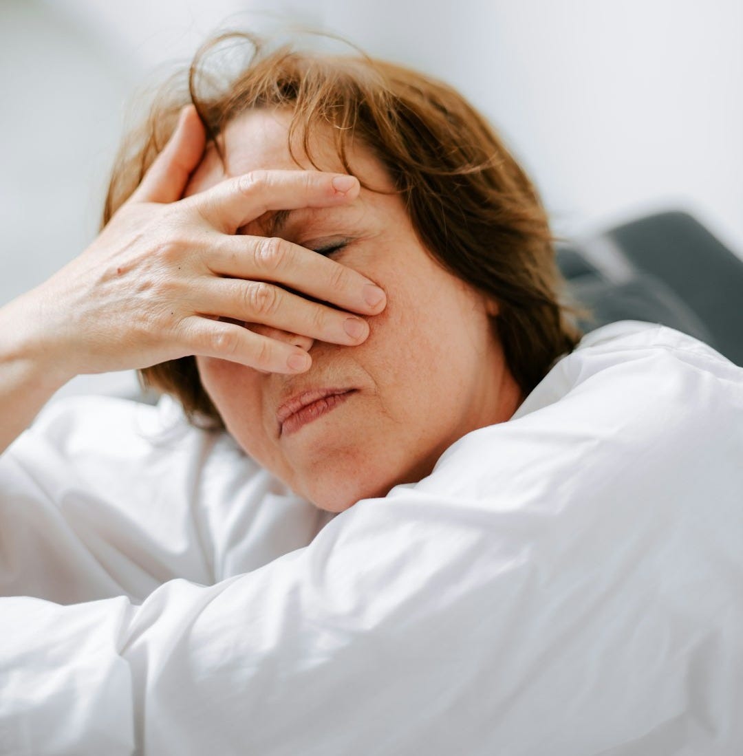 a woman laying in bed with her hands on her head
