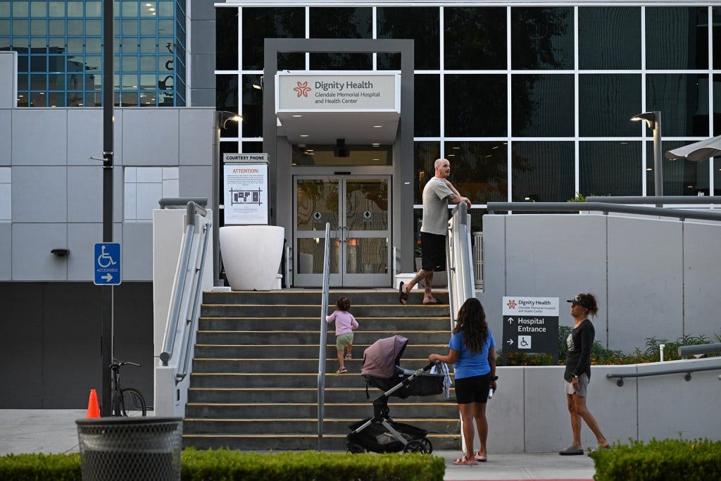 Exterior view of Dignity Health Glendale Memorial Hospital, with people gathered on the front steps. A child walks up the stairs while others stand and talk nearby. Exterior view of Dignity Health Glendale Memorial Hospital, with people gathered on the front steps. A child walks up the stairs while others stand and talk nearby.
