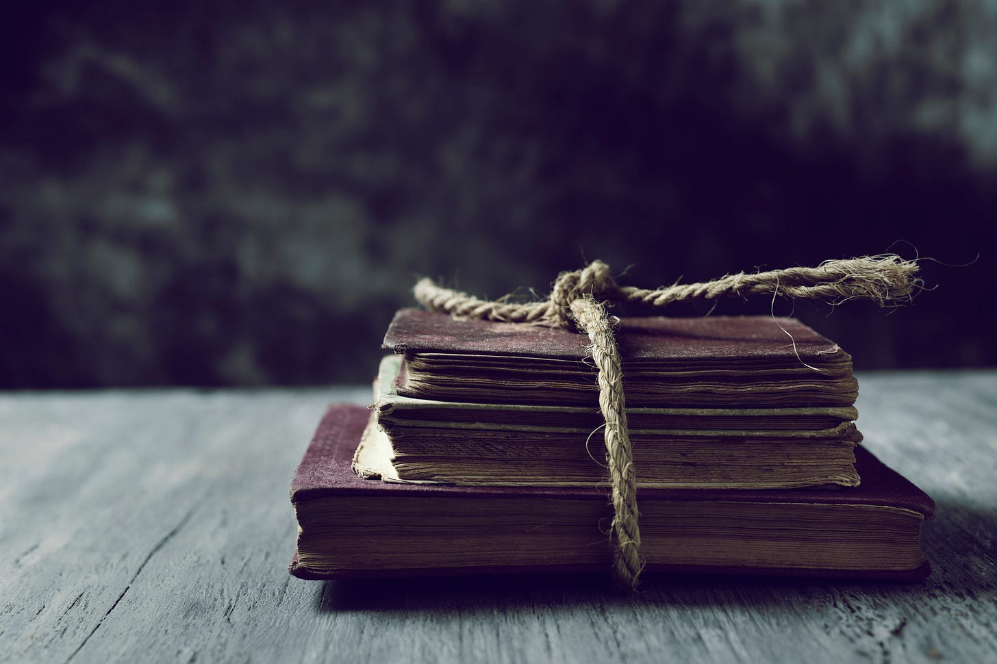 brown books tied with rope on wooden table