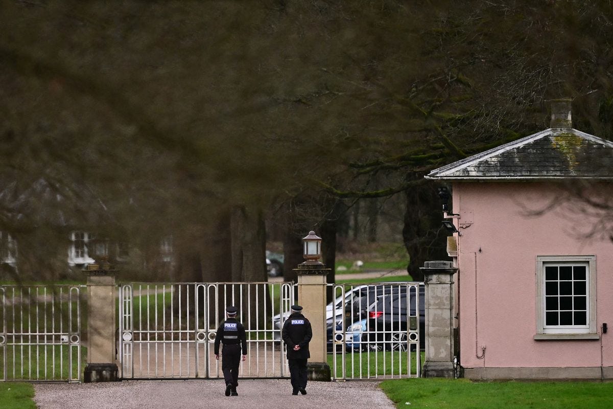 Police officers walk towards the entrance to Royal Lodge
