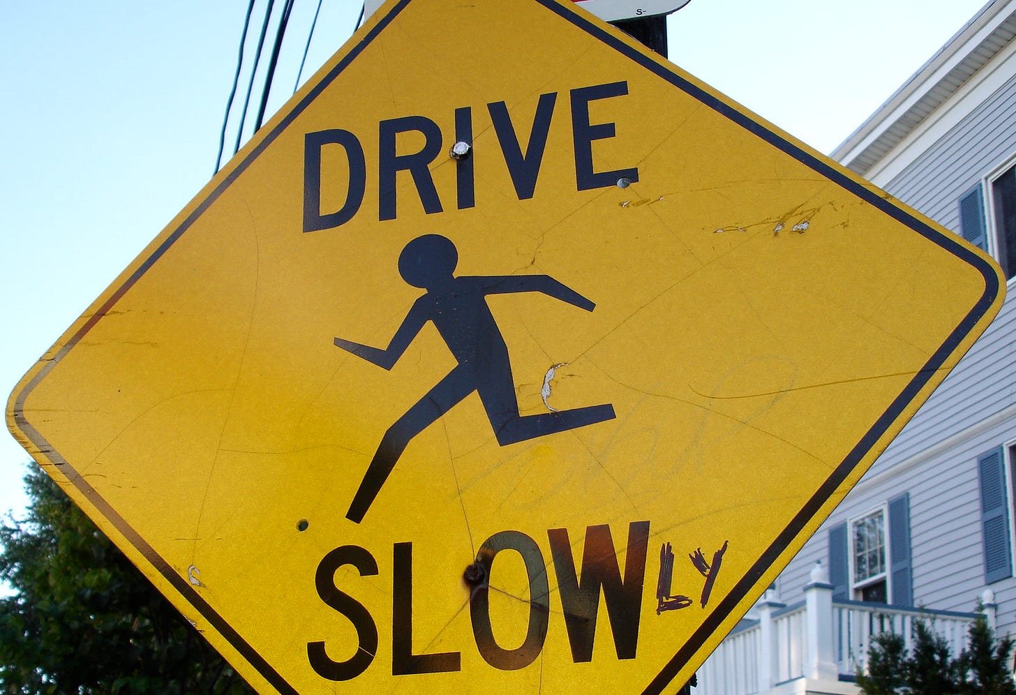 A sign that originally read "DRIVE SLOW" corrected to read "DRIVE SLOWLY"