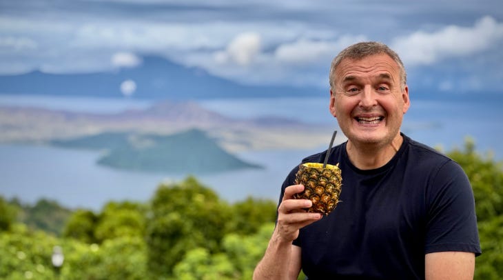 Phil Rosenthal holding a pineapple and smiling for the camera