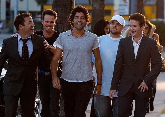 This may contain: four men are walking down the sidewalk together This may contain: four men are walking down the sidewalk together
