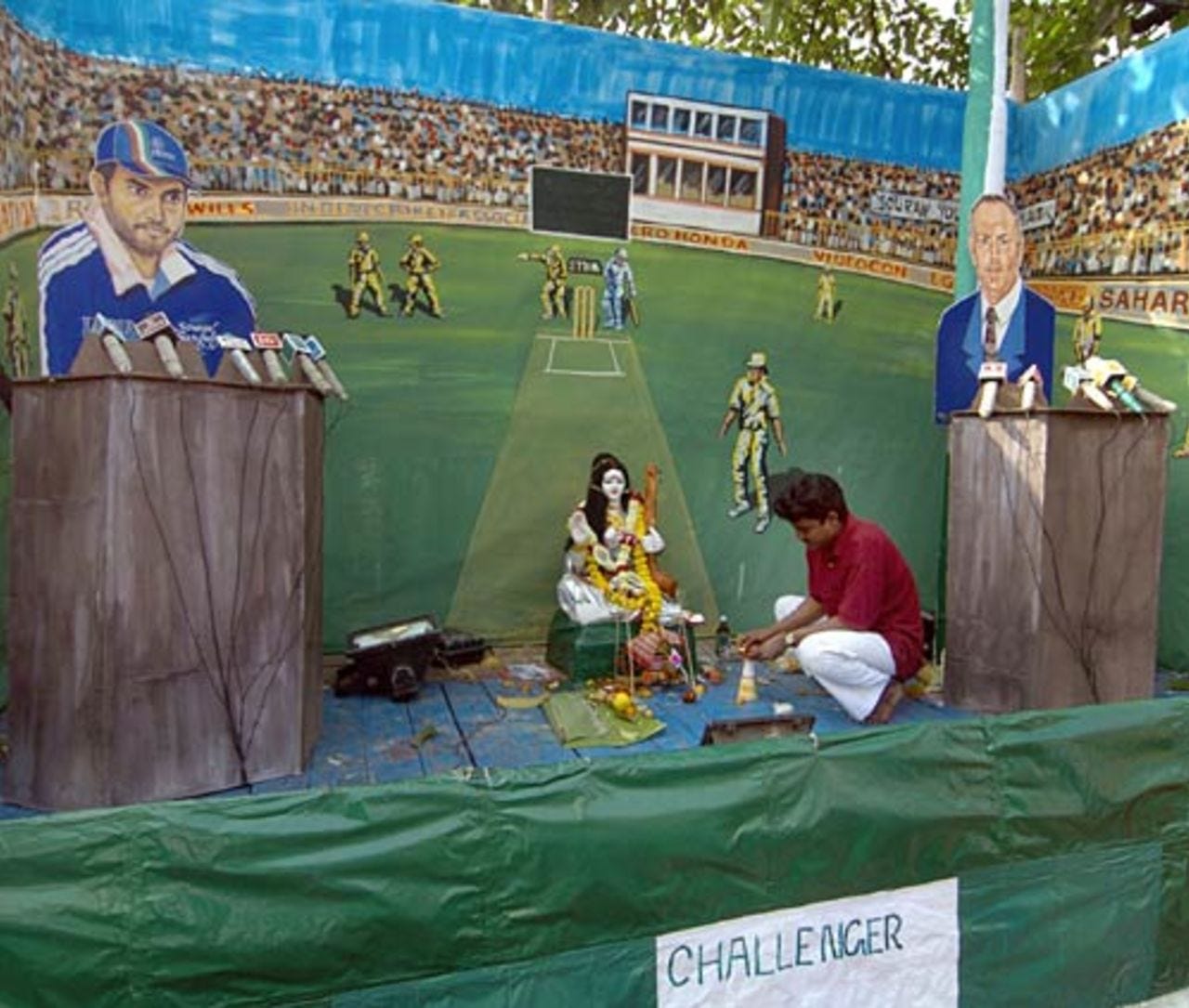 A worker lights-up a candle, a ritual of worshipping Sarasawati, (idol in the middle) Hindu goddess of knowledge, music and creative arts, while the worship place has been decorated by cut-outs of  Sourav Ganguly and Greg Chappell, depicted as challenger, Kolkata, India, February 4 2005