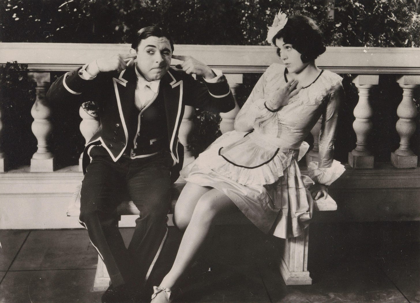A man and a woman playfully acting on a bench.
