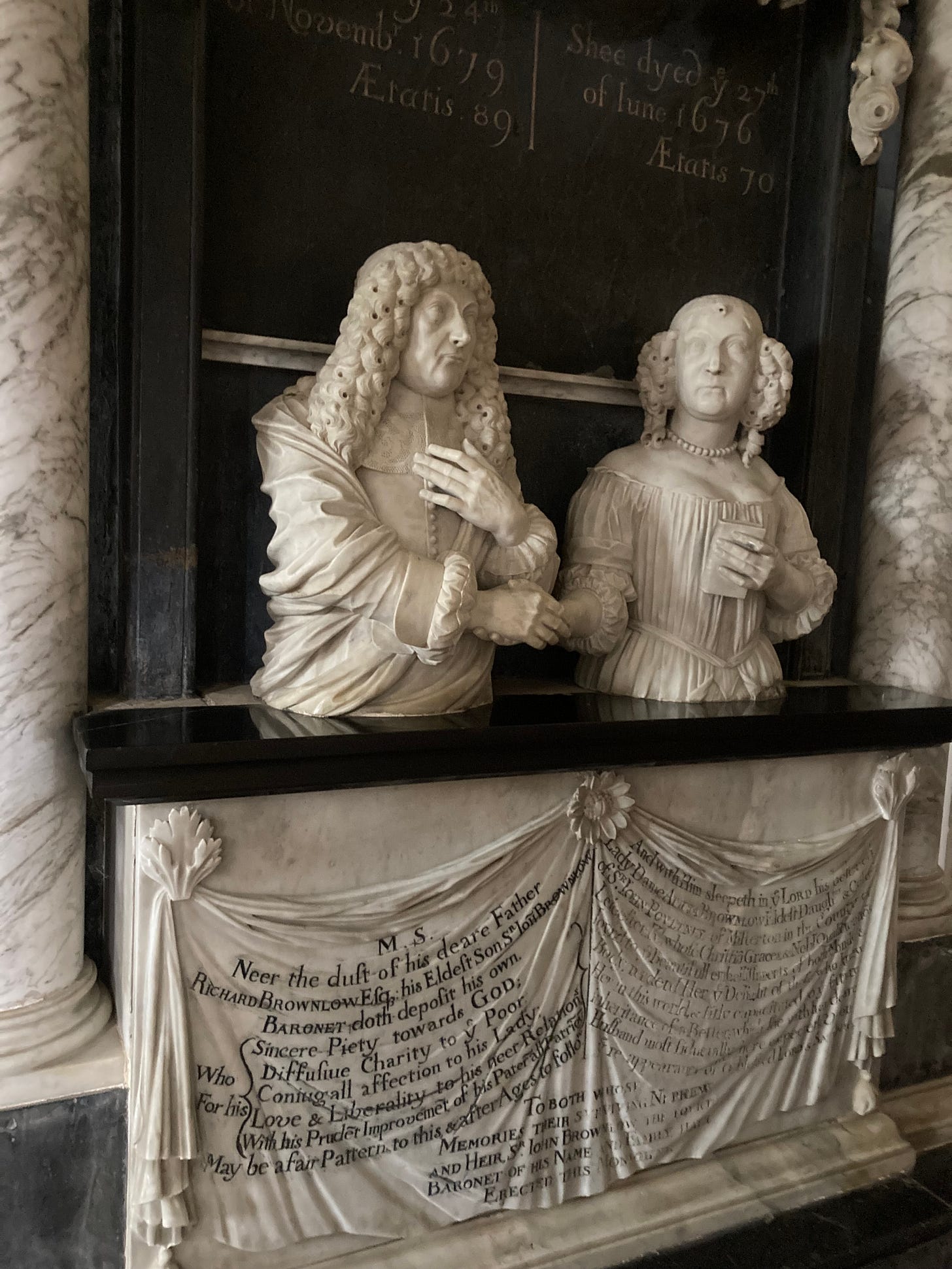 Elaborate 17th century stone statues of a noble man and woman standing near a burial vault