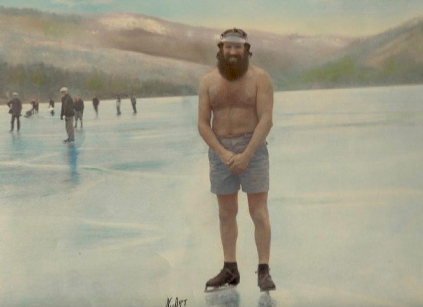 Hand-colored photograph of Willie Willey standing bare-chested in shorts and boots on a frozen body of water in Spokane, smiling toward the camera while other bundled figures skate in the distance against a snowy, mountainous backdrop.