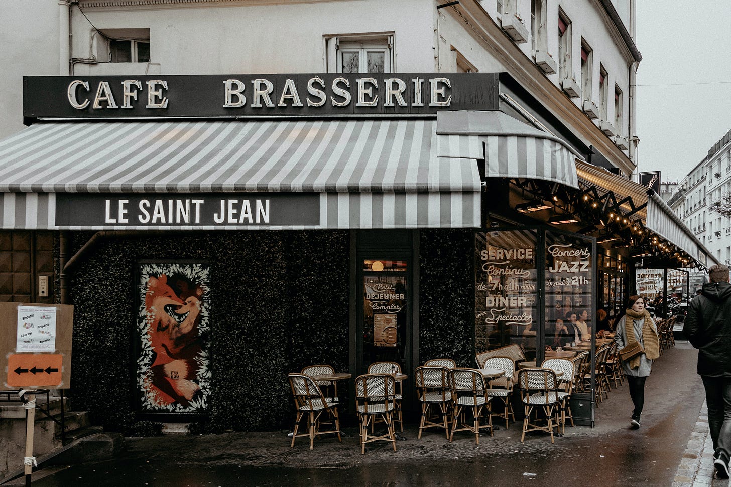 A cafe in Paris with a sidewalk patio, people walking, a rainy day. A cafe in Paris with a sidewalk patio, people walking, a rainy day.